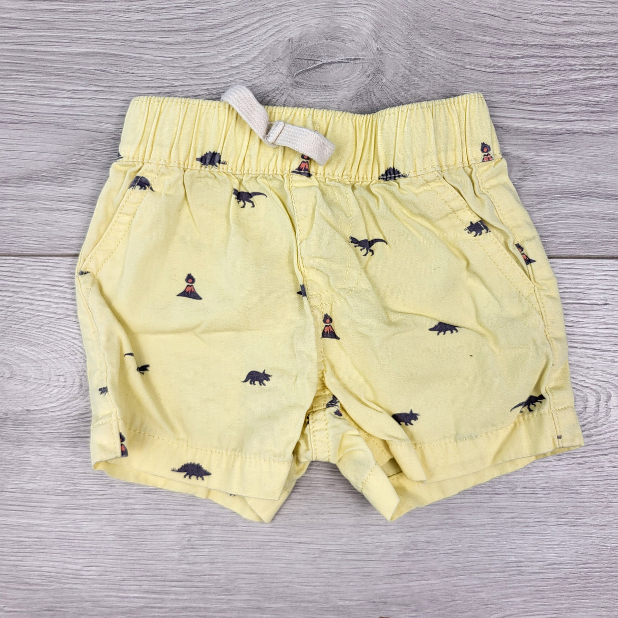 PRCH1 - Children's Place yellow shorts with volcanoes and dinosaurs. Size 0-3 months