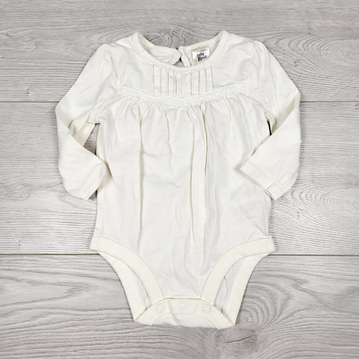 ECRS11 - Oshkosh white long sleeved bodysuit with pleat detail. Size 6 months