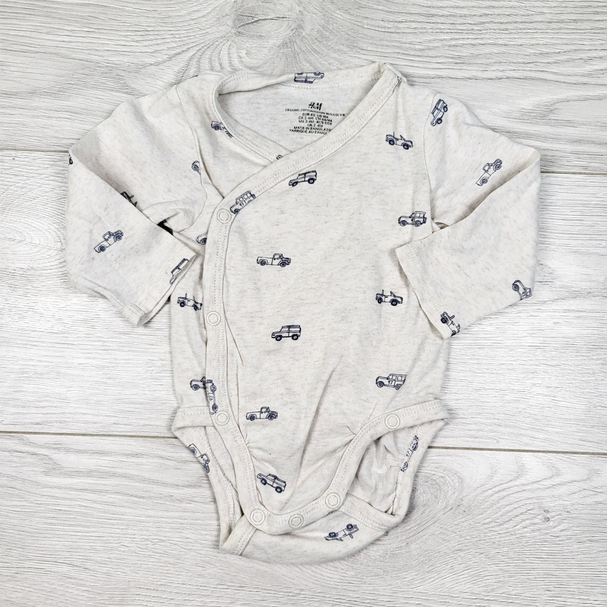 H and M light grey organic cotton wrap style bodysuit with trucks. Size 2-4 months