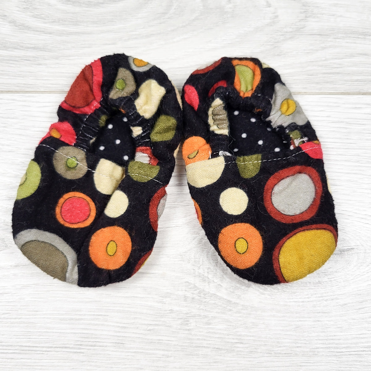 Black circle print soft soled slippers. Approx 0-6 months